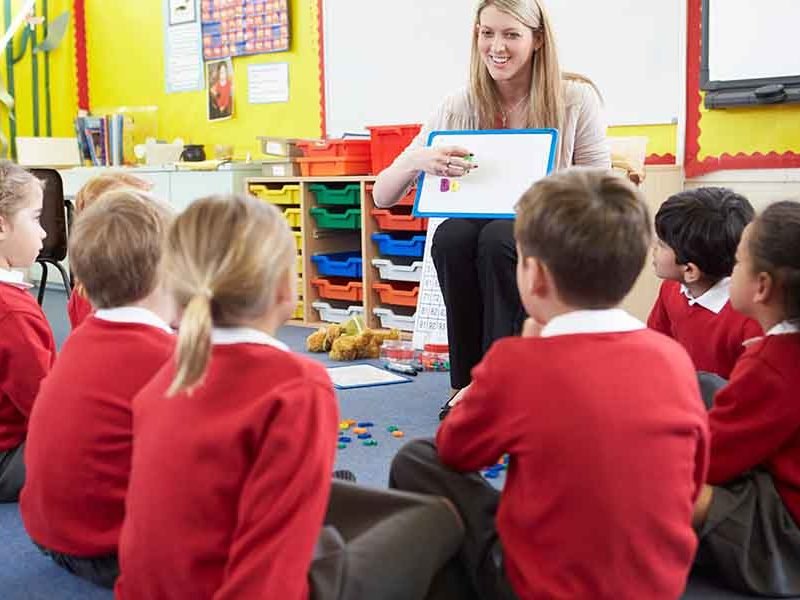 Teacher Teaching Spelling To Elementary School Pupils